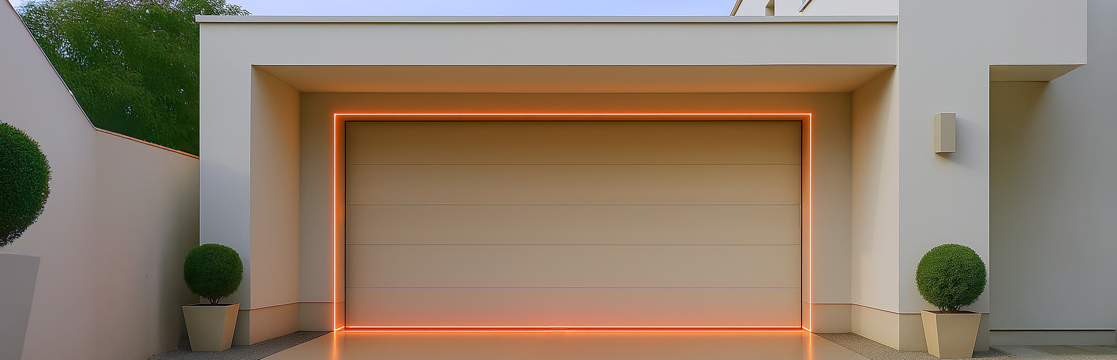 Eine moderne weiße Garage mit klaren Linien, akzentuiert durch einen leuchtenden orangefarbenen LED-Streifen um den Torrahmen. Zwei runde Topfsträucher stehen symmetrisch auf beiden Seiten der Einfahrt.