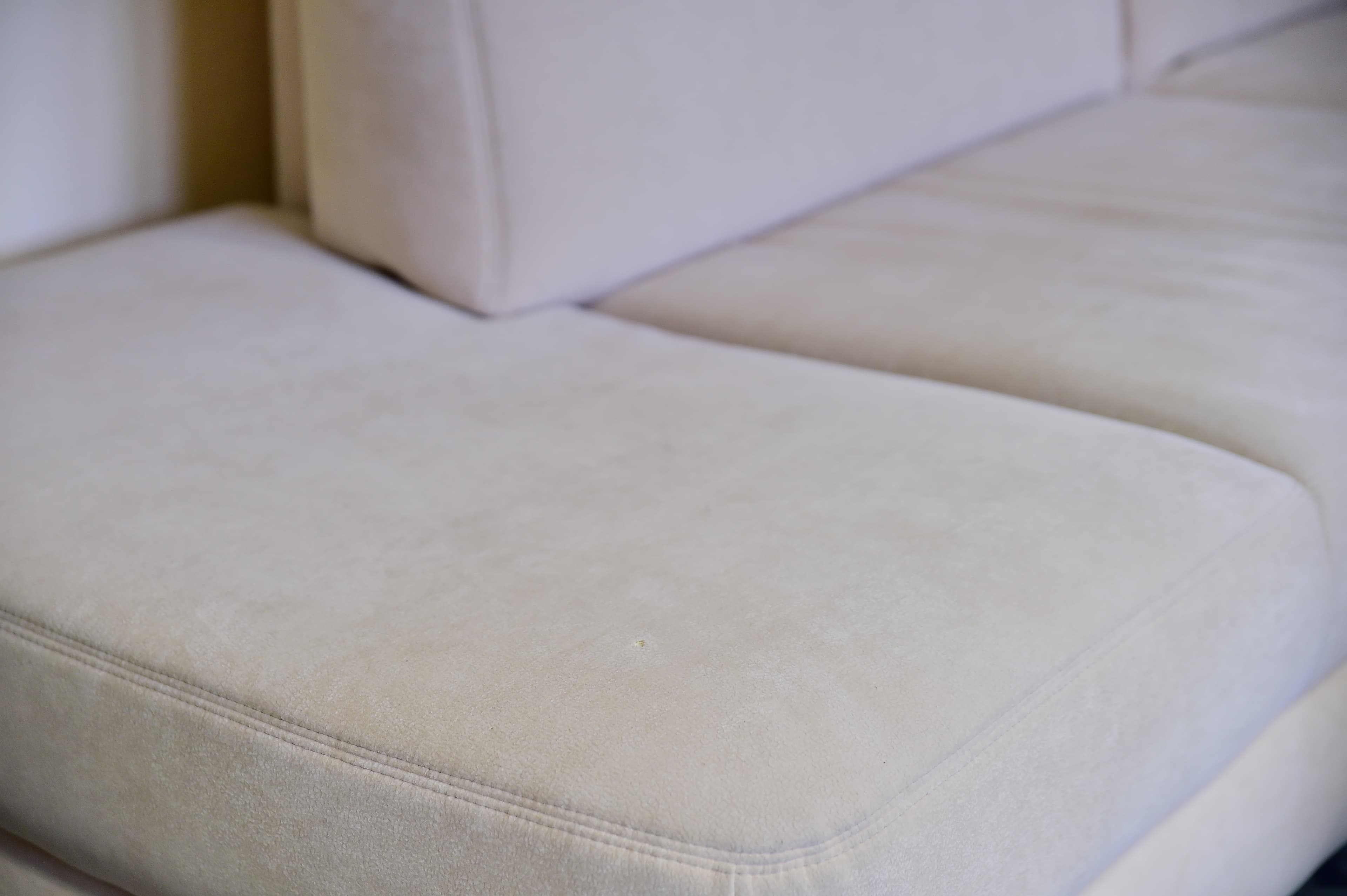 Nahaufnahme eines hellbeigen Sofas mit weichen, plüschigen Kissen und sichtbaren Nähten entlang der Nähte.
