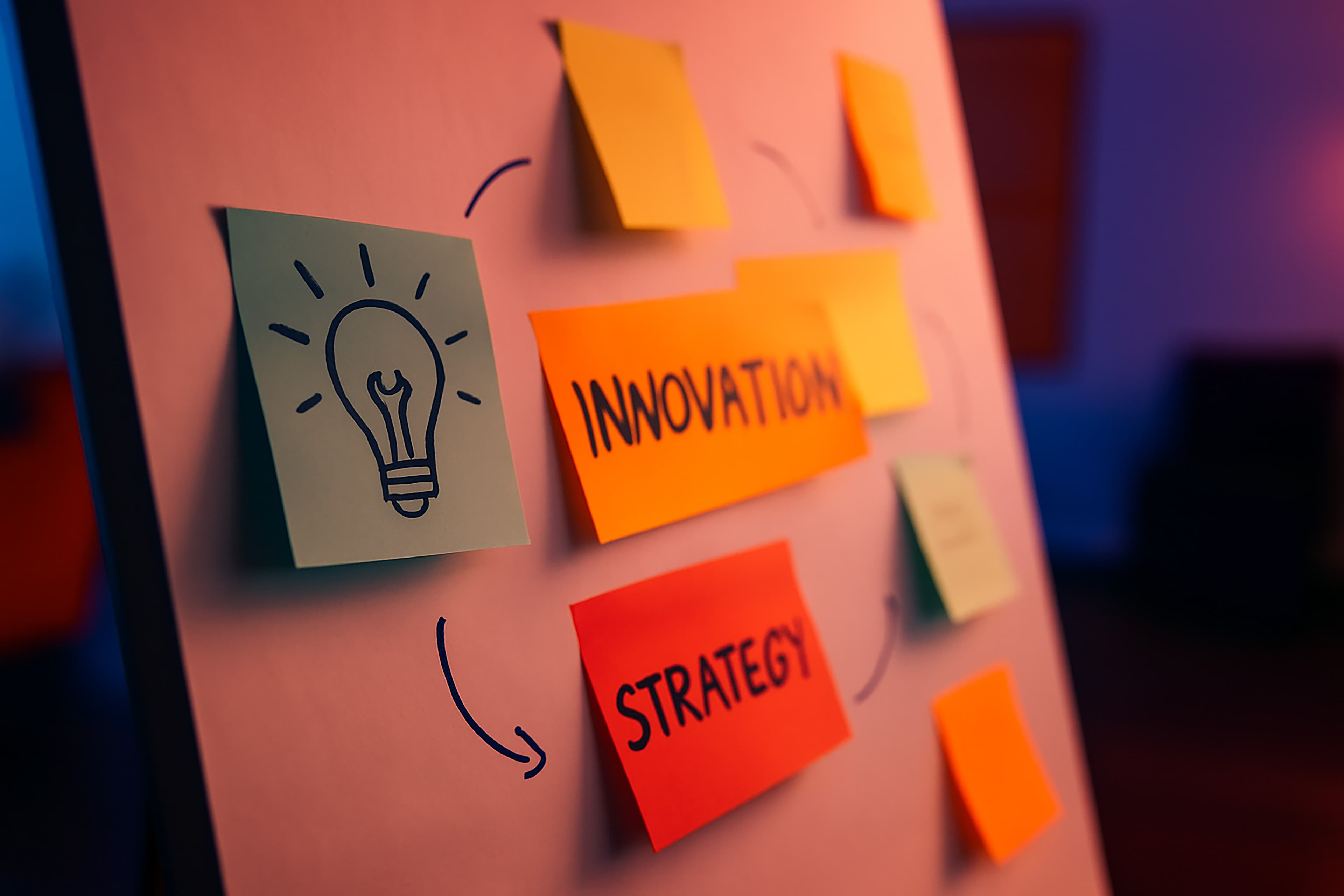 Un tableau blanc avec des notes autocollantes colorées, comprenant des dessins et des mots comme INNOVATION et STRATÉGIE, reliés par des flèches, suggérant un brainstorming ou une planification dans un environnement de bureau créatif.
