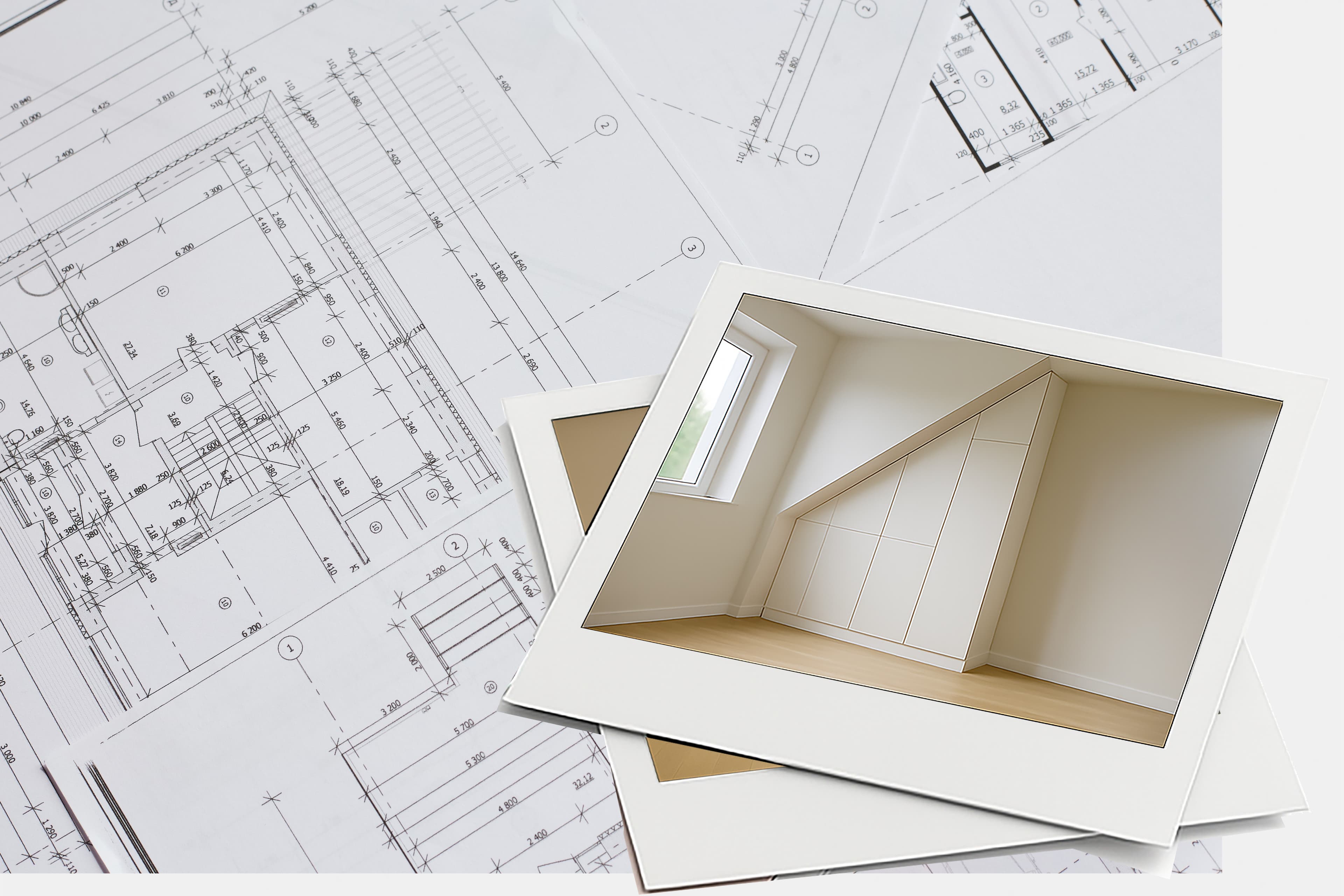 Two polaroid photos showing a modern, built-in storage unit under a slanted ceiling are placed on top of architectural blueprints with detailed floor plans and measurements.